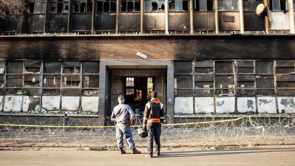 A police officer and security guard stand in front of the gutted 80 Albert Street building, where at least 73 people died in a fire, in downtown Johannesburg, South Africa, 01 September 2023