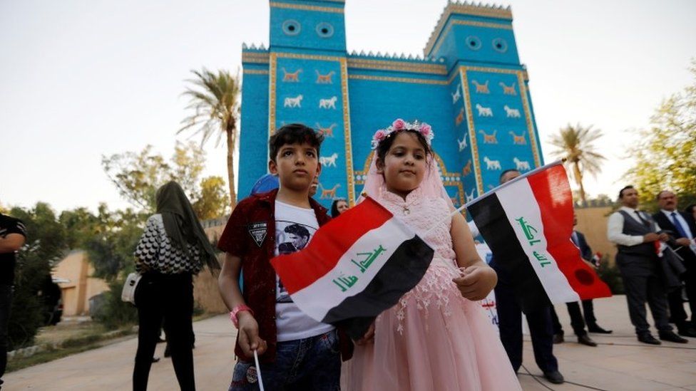 Children hold Iraqi flags during celebrations after Unesco designated Babylon as a World Heritage Site, in front of a replica of Ishtar gate near Hilla, Iraq, July 5, 2019.