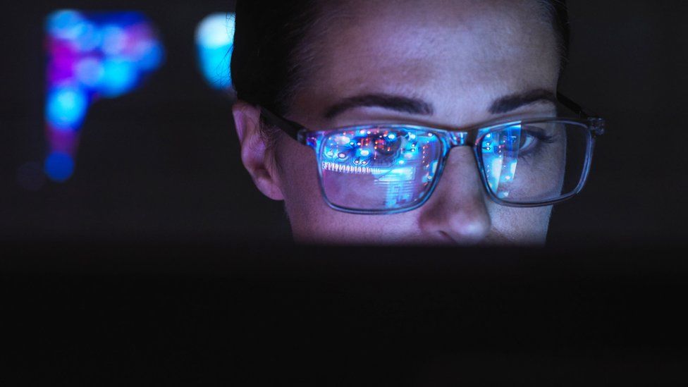 Ingeniero diseñando tecnología de IA con la pantalla del ordenador reflejándose en sus gafas
