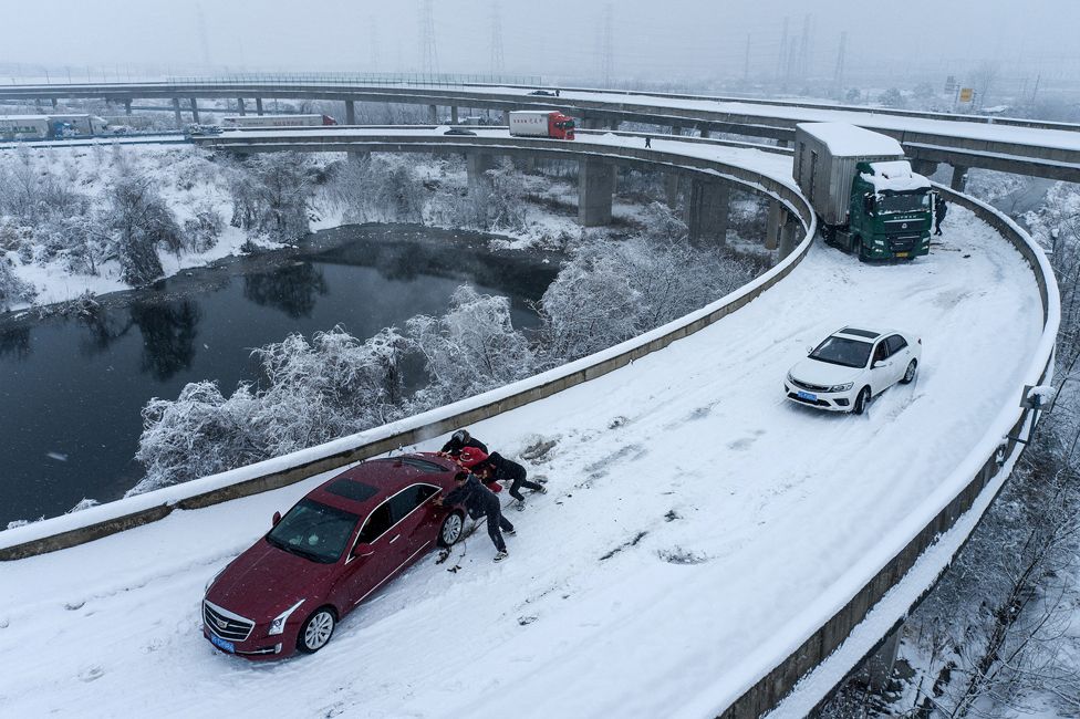 People push a car stuck on a highway following heavy snowfall in the region, during the Spring Festival travel rush ahead of the Chinese Lunar New Year, in Wuhan, Hubei province, China. 6 February 2024.