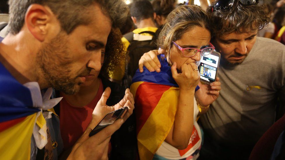 Independence supporters listen to Carles Puigdemont's speech on phones in Barcelona, 21 October