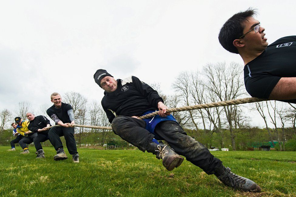 A group of men strain at a tug of war rope.