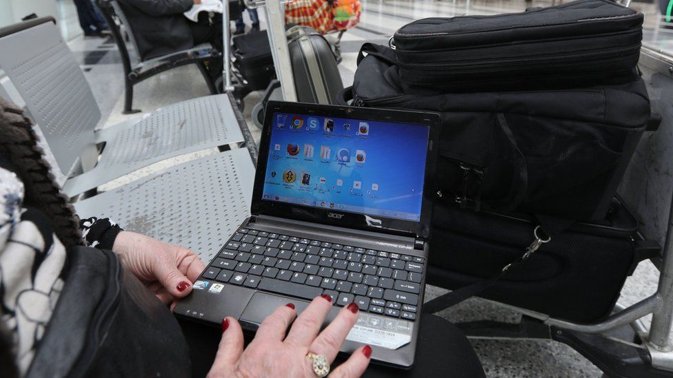 A Syrian woman travelling to the United States through Amman opens her laptop before checking in at Beirut international airport