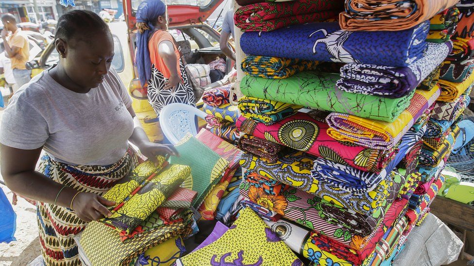 A market woman folding cloth at her stall in Monrovia, Liberia - Tuesday 19 November 2019