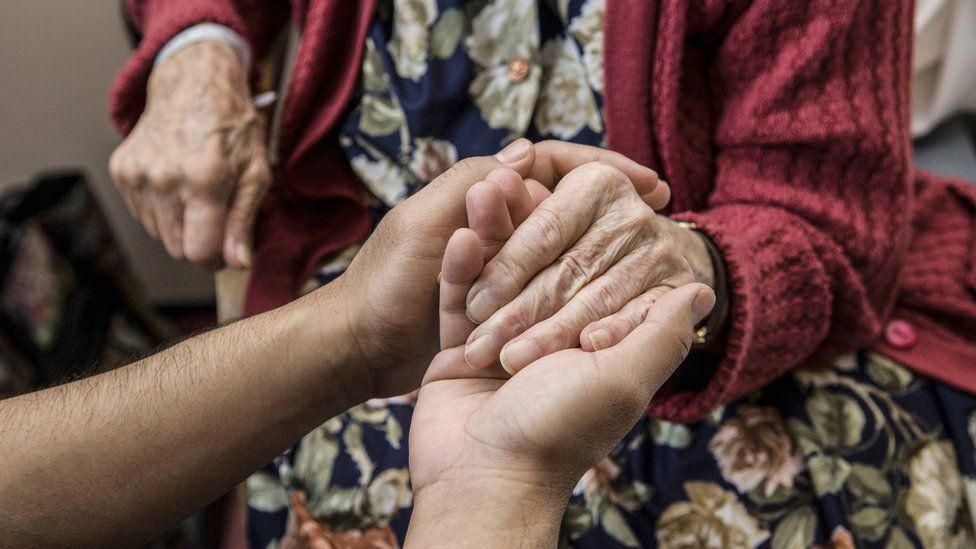 An elderly woman's hands being held