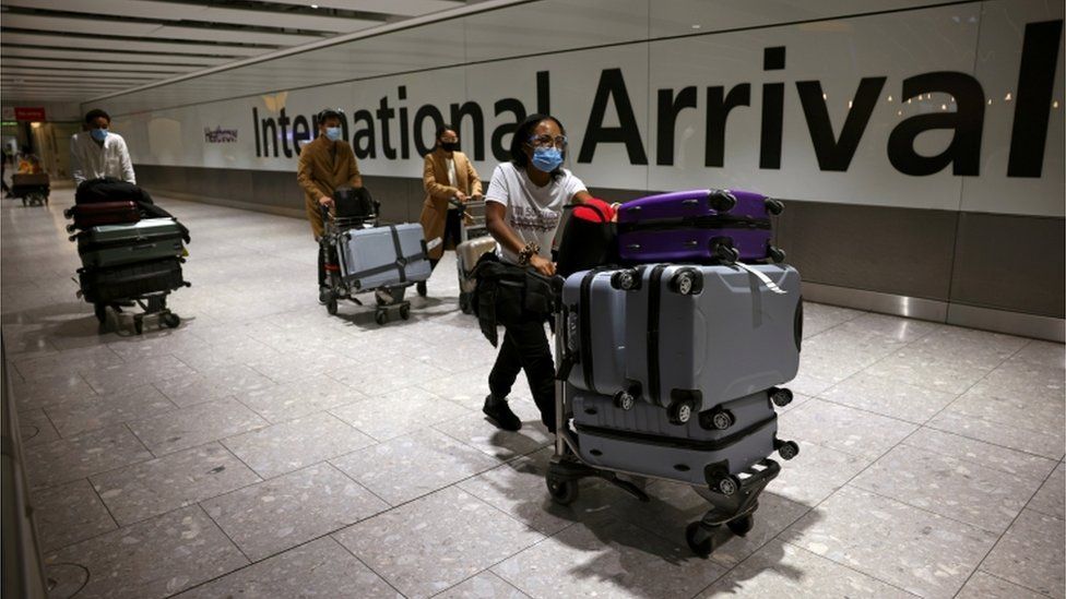 Travellers walk through the arrivals area at Heathrow Airport
