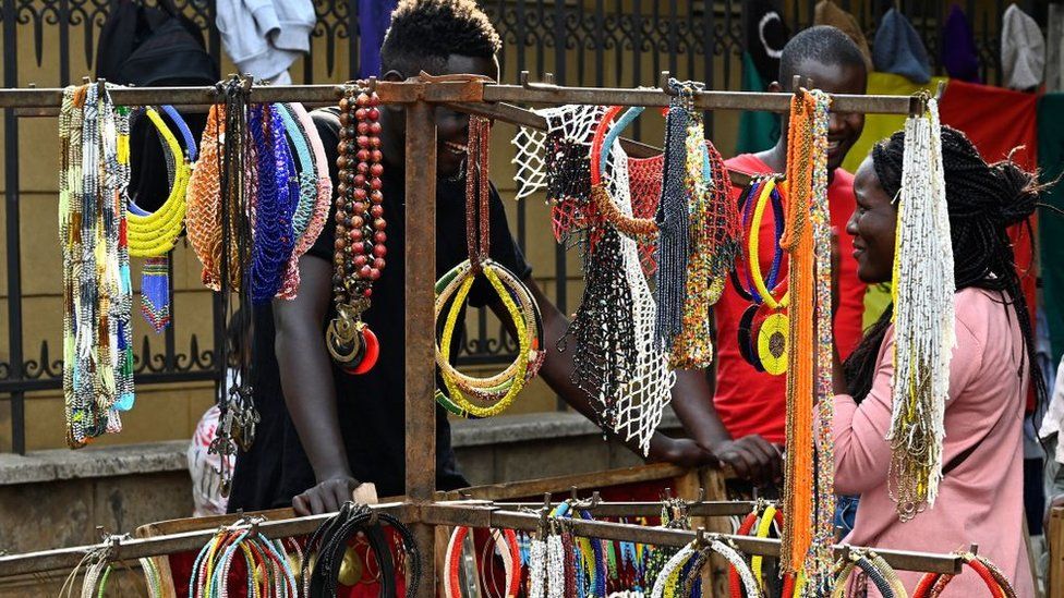 A visitor speaks to a man running a stall selling beaded necklaces displayed at the Maasai market in Nairobi on June 16, 2019