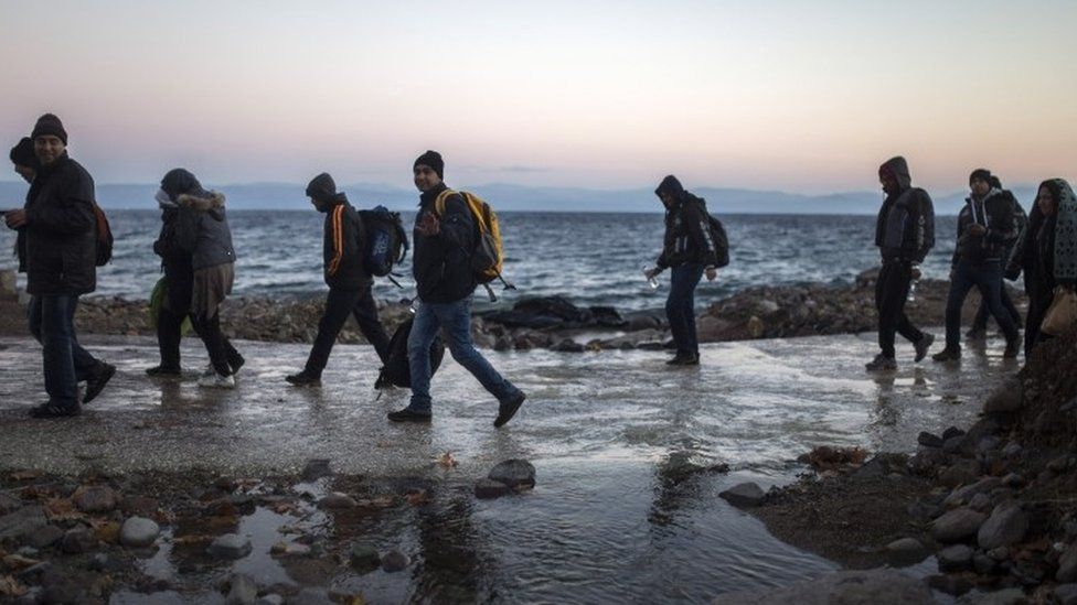 Afghan refugees walk on a beach after their arrival from the Turkish coast to the north-eastern Greek island of Lesbos (30 November 2015)