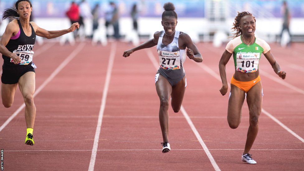 Finish line photo featuring three athletes as Marie-Josee Ta Lou in Ivorian colours wins the 100m at the 2019 African Games in Rabat