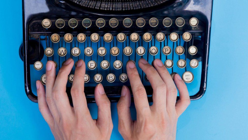 Hands typing on a manual "qwerty" typewriter
