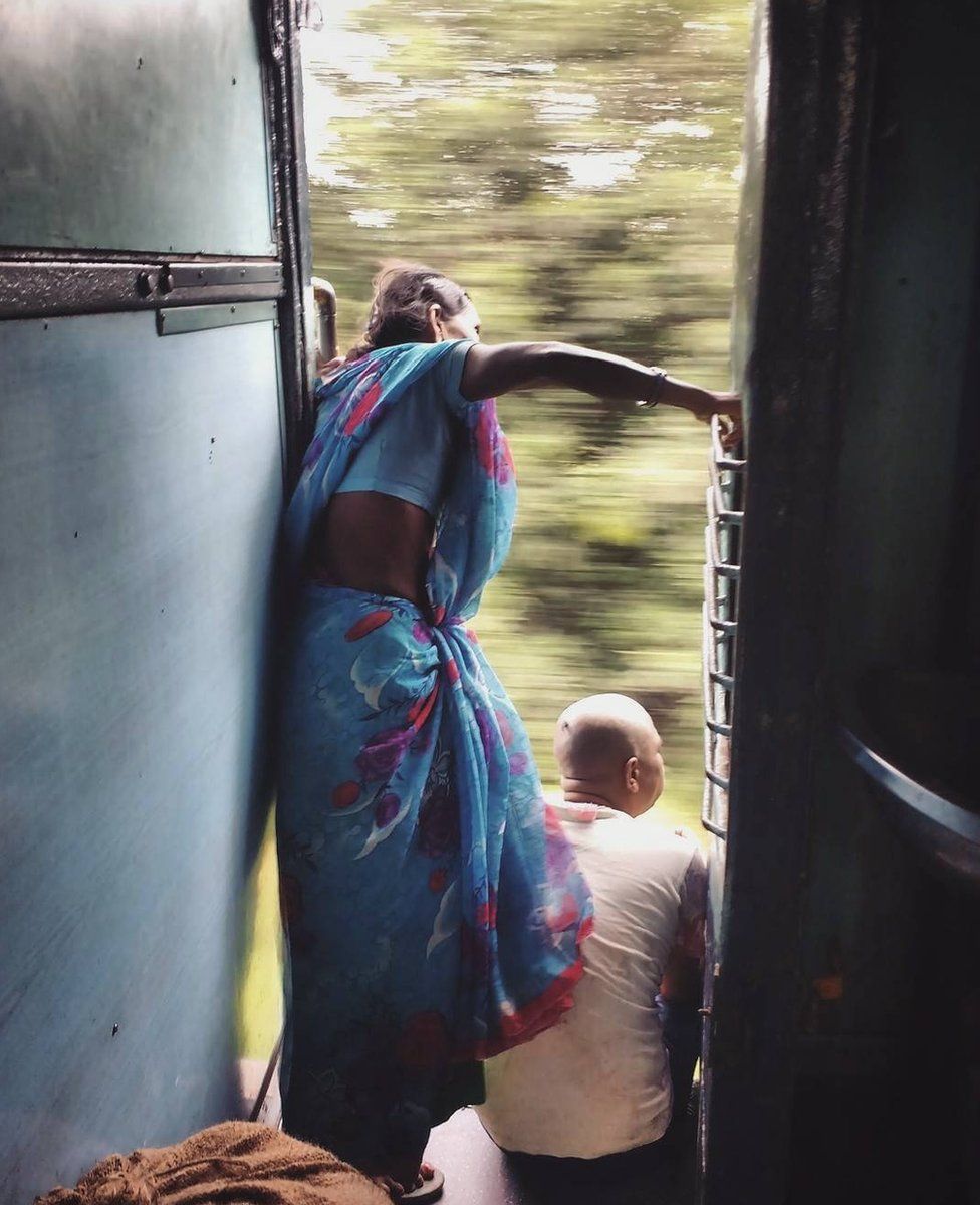 A woman peers out of a moving train, looking for her stop.