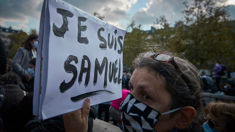 A protester wearing a face mask holds a sign in French that reads: 'I am Samuel'