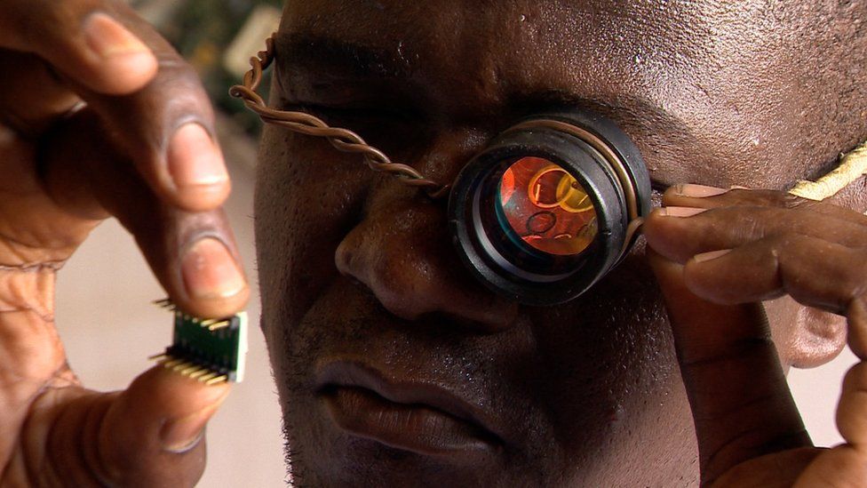 Woora Make lab founder Gnikou Afate examines a microchip using this rudimentary magnifier
