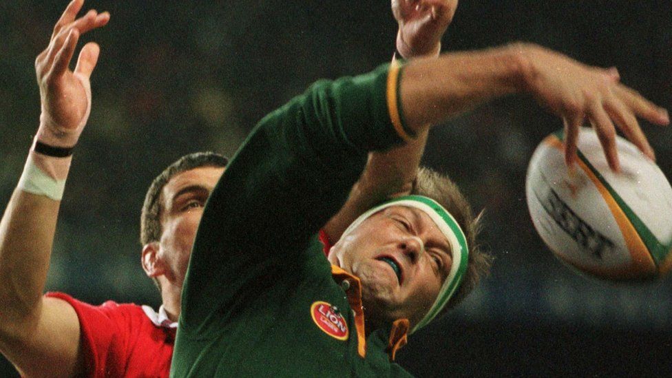 South African forward Hannes Strydom (R) reaches for the ball as British Lions captain Martin Johnson is behind him
