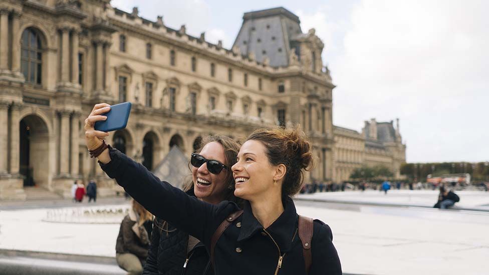 two tourists taking selfies at the Louvre, Paris