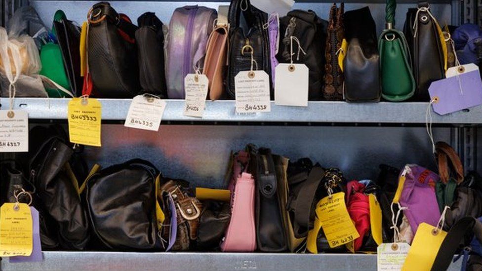 Image of shelves containing rows of handbags, with numbered tags hanging from them