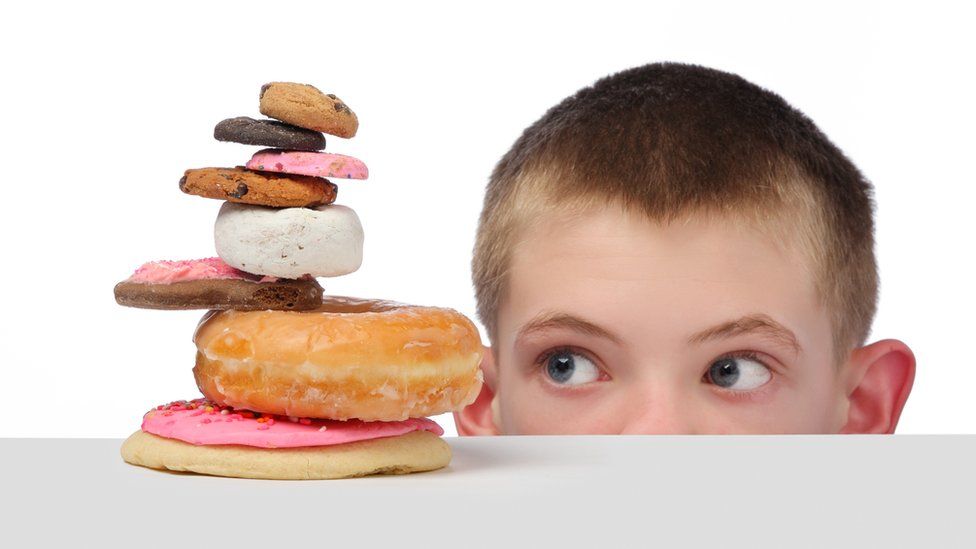 Boy looking at a pile of sugary food