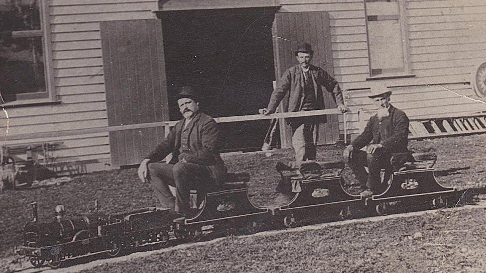 Charles Wilson y sus hijos fotografiados con una maqueta de locomotora en la Feria de Pascua de Bendigo, Australia, en 1895