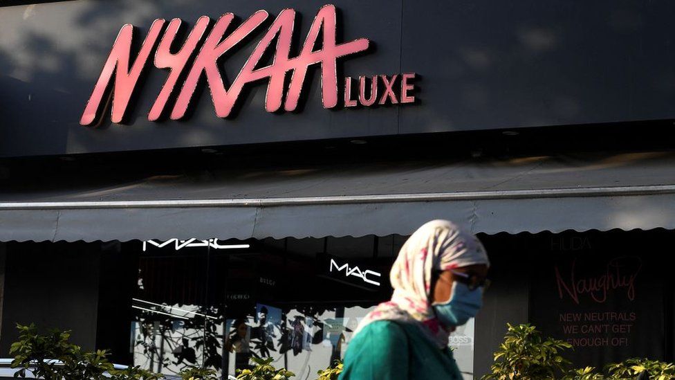 In this picture taken on December 29, 2021, a woman walks past a store for beauty products platform Nykaa in Mumbai.