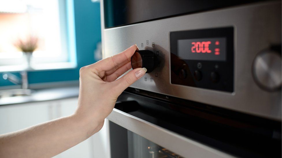 Close up of woman's hand setting temperature control on oven.