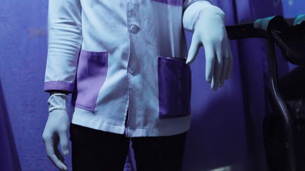 Person in a white coat with surgical gloves