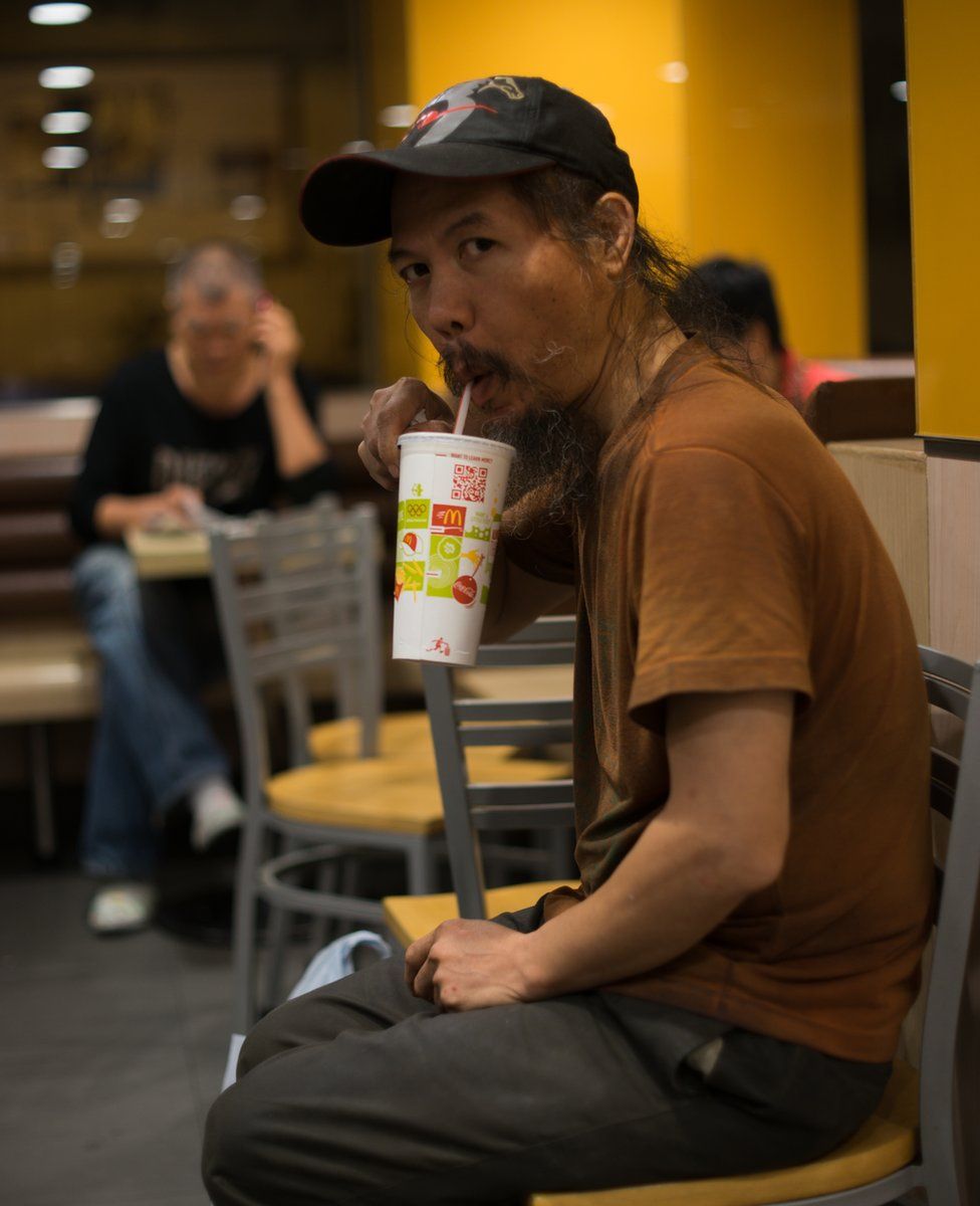 A man drinks a soft drink in McDonalds