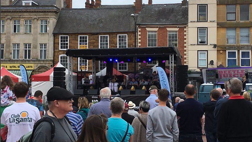 A band playing on stage in Market Square with people watching