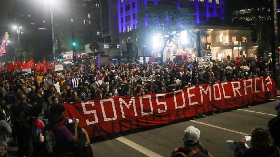 Demonstrators in São Paulo march with a big banner with the words "We are democracy" in Portuguese. Photo: 9 January 2023