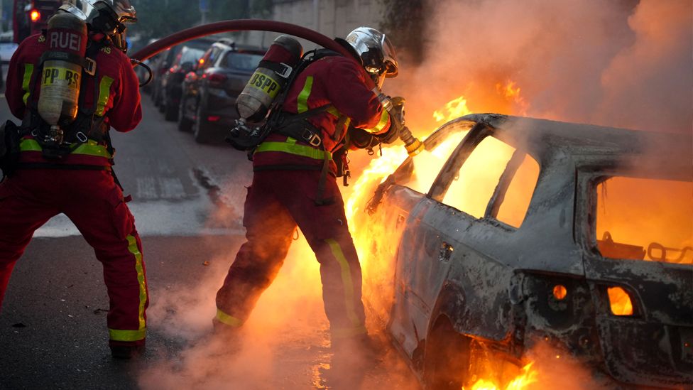 I vigili del fuoco spengono un veicolo in fiamme distrutto dai manifestanti a Nanterre, a ovest di Parigi, il 27 giugno 2023