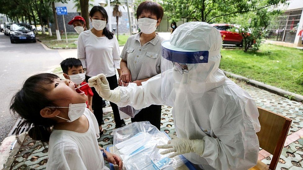 A medical worker takes a swab sample from a child to be tested for coronavirus in a street in Wuhan