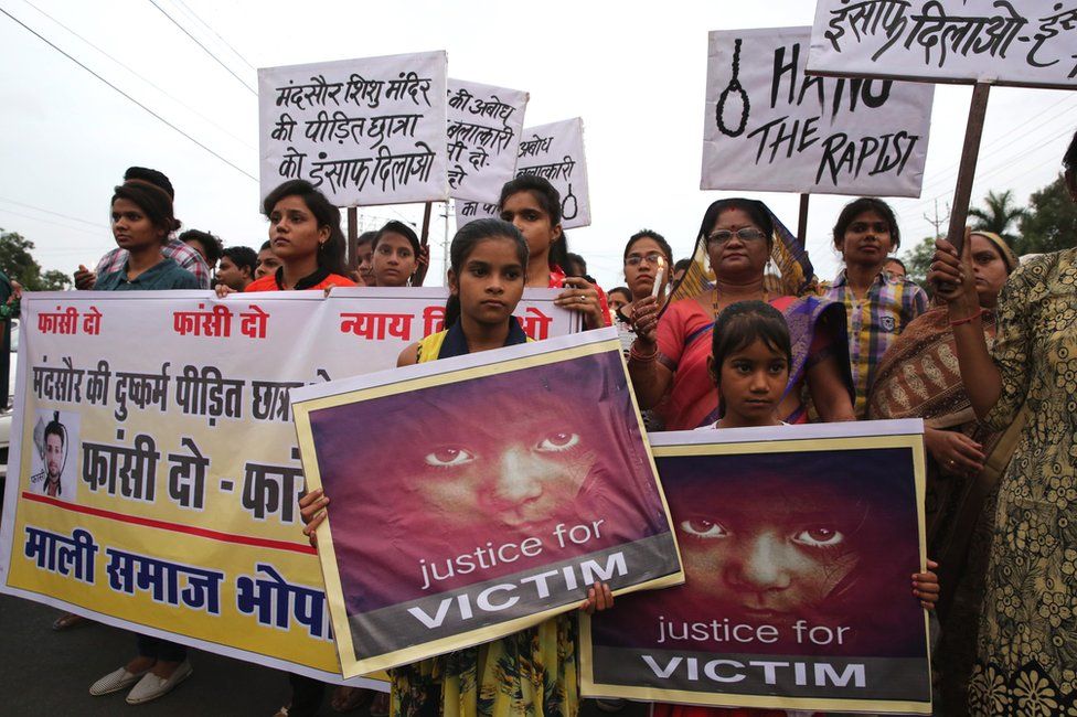 People hold posters and candles during a march to protest against the rape of a seven-year-old girl in Mandsaur.