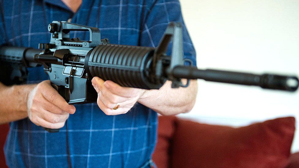 File picture of a man holding a Colt AR-15 semi-automatic rifle