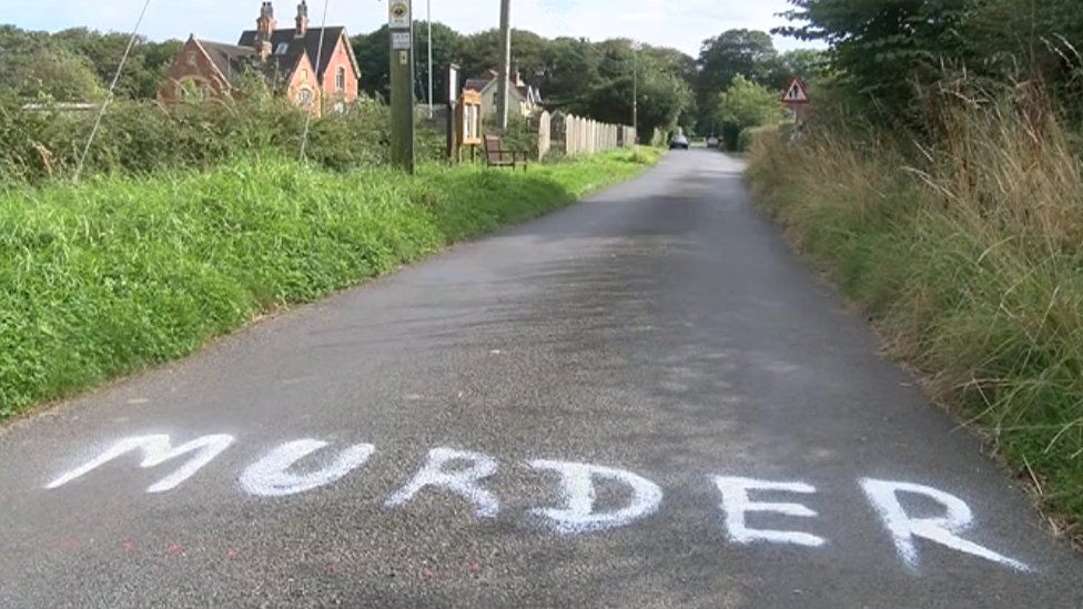 The word "murder" spray painted on a road
