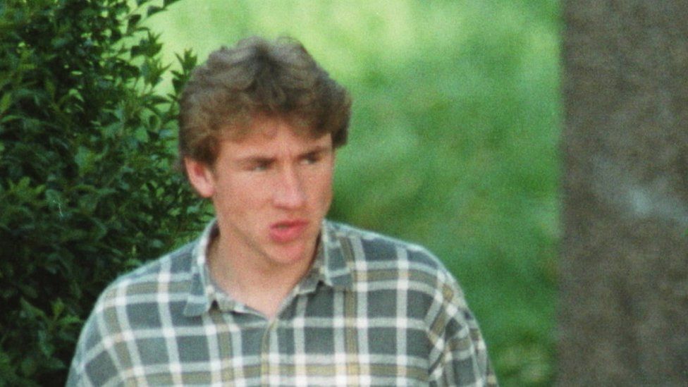 Matthew White, wearing a green checked shirt, pictured in a police surveillance photo