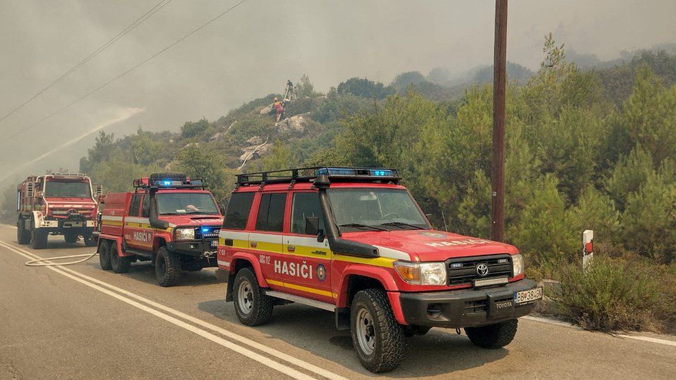 Πυροσβεστικά οχήματα παρατάσσονται καθώς οι πυροσβέστες προσπαθούν να σβήσουν μια πυρκαγιά που καίει κοντά στη Λάερμα της Ρόδου