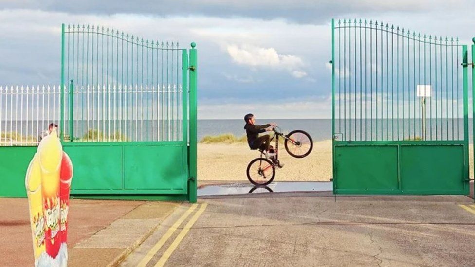 A boy on Great Yarmouth seafront performing a BMX wheelie