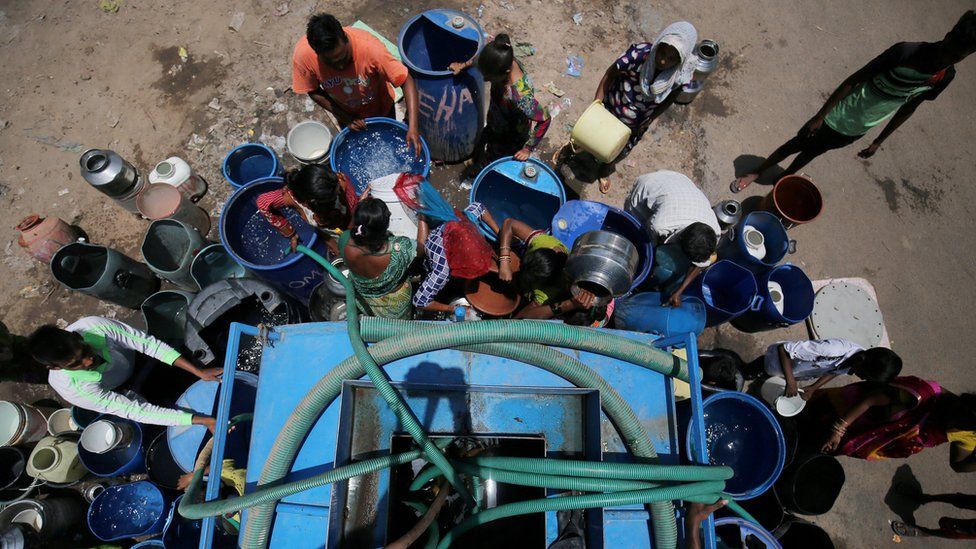People collect water from a tanker in India