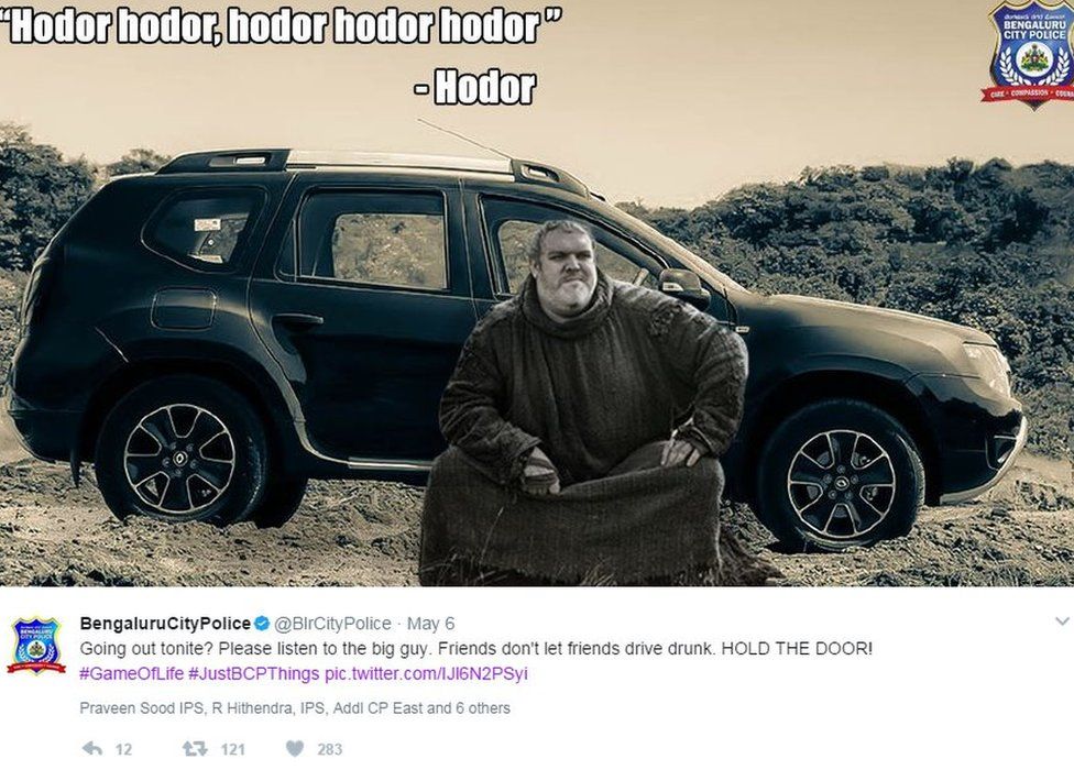 An image of Hodor sitting in front of a car door. Bangalore police comment: "Going out tonight? Please listen to the big guy. Friends don't let friend's drive drunk. Hold the Door!"