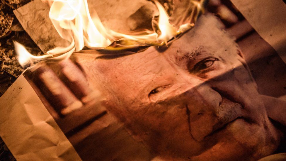 Image shows a burning photograph of Fethullah Gulen