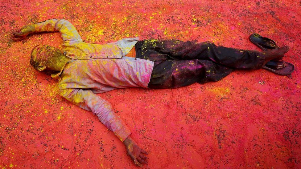 A Hindu devotee, smeared in coloured powder, takes a rest on a road during a procession for Holi celebrations in Kolkata