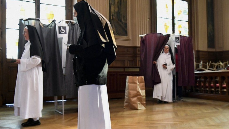Nuns prepare to vote in the second round of the 2022 French presidential election at a polling station in Paris