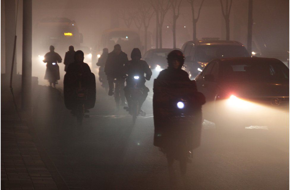 Cyclists ride along a road in heavy smog on 23 December 2015 in Beijing, China