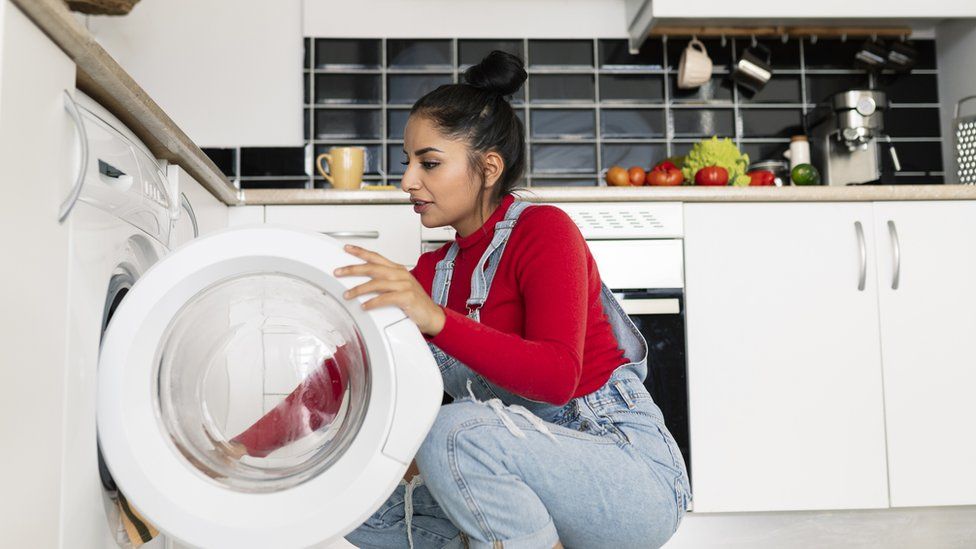 Женщина загружает стиральную машину | ||