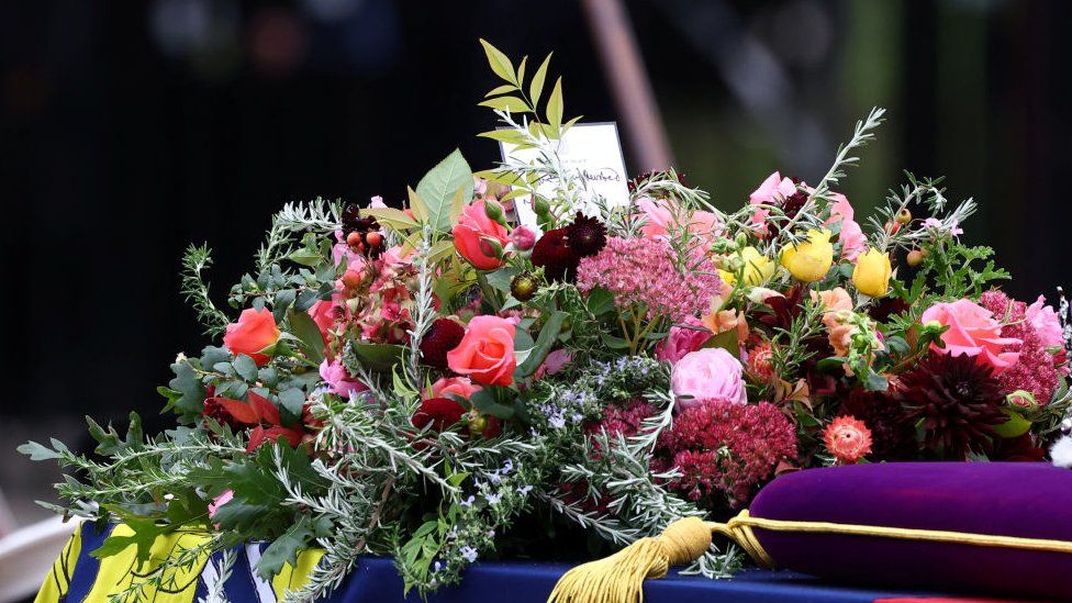 A handwritten card on top of the Queen's coffin reads: "In loving and devoted memory. Charles R".