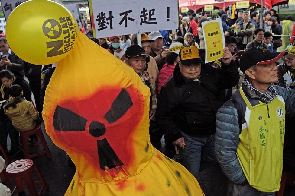 Protesters walk past a nuclear face effigy (L) during an anti-nuclear energy demonstration in Taipei on 12 March 2016.