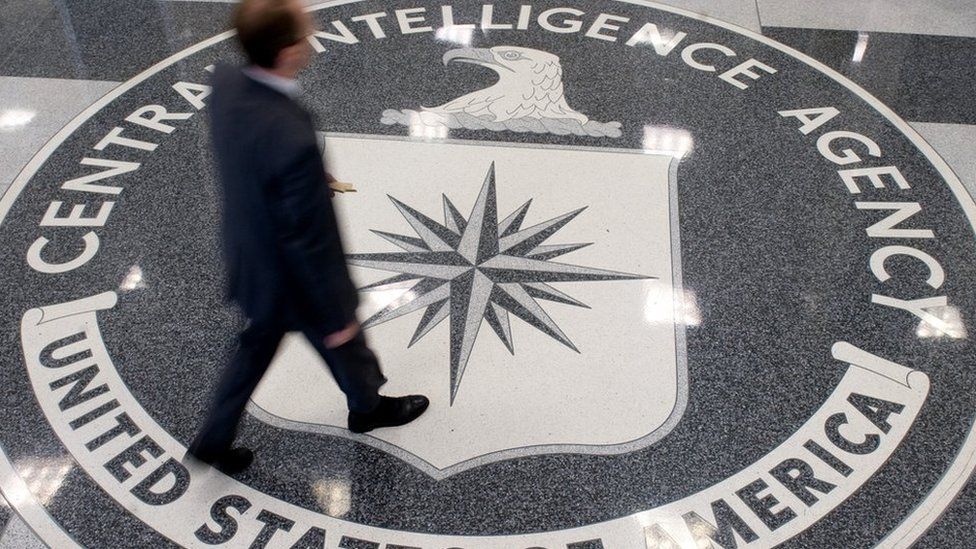 A man crosses the Central Intelligence Agency (CIA) seal in the lobby of CIA Headquarters