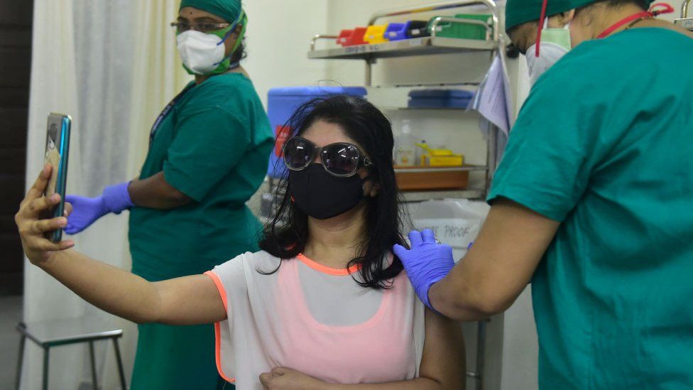 A woman taking a selfie while getting vaccinated