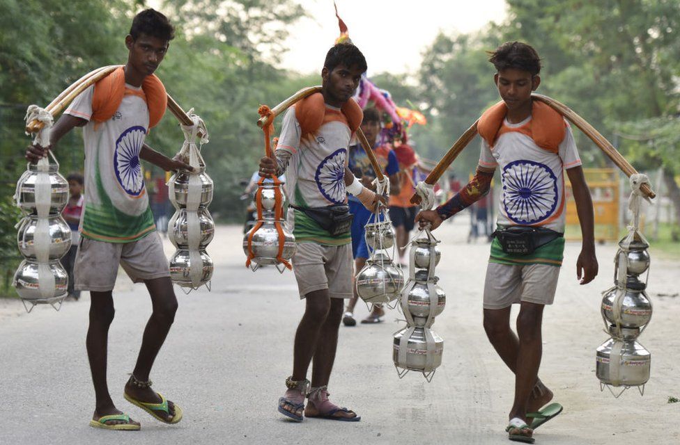 Kanwariyas wearing t-shirts with the Indian national flag printed on them carry holy water in pots on 19 July 2017.