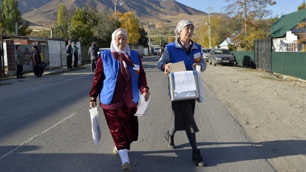 Members of a local electoral commission walk with a ballot box during an early voting in the presidential election in the village of Arashan some 20 km from Bishkek on October 14, 2017