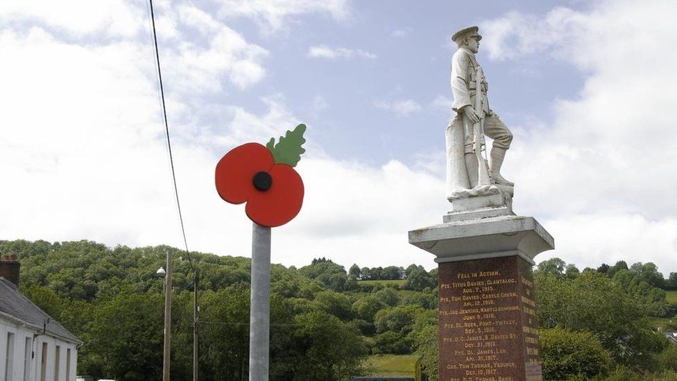 Poppy on sign next to war memorial